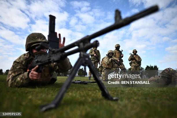 Ukraine Army recruits watch as a colleague uses a GPMG during a live firing training session with members of Britain's and New Zealand's armed forces...