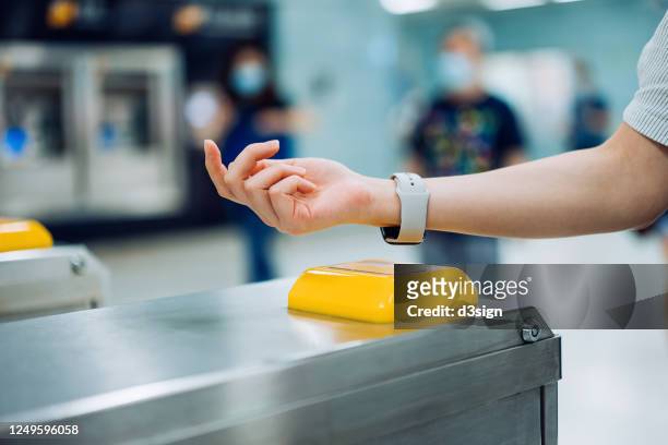 cropped shot of young asian woman checking in at subway station using contactless payment for subway ticket via smartwatch - paying stock-fotos und bilder