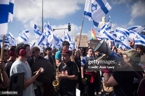 Protestors wave flags as thousands of Israelis attend a rally against Israeli Government's judicial overhaul plan on March 27, 2023 in Jerusalem,...