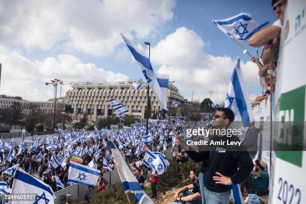 Protestors wave flags as thousands of Israelis attend a rally against Israeli Government's judicial overhaul plan on March 27, 2023 in Jerusalem,...