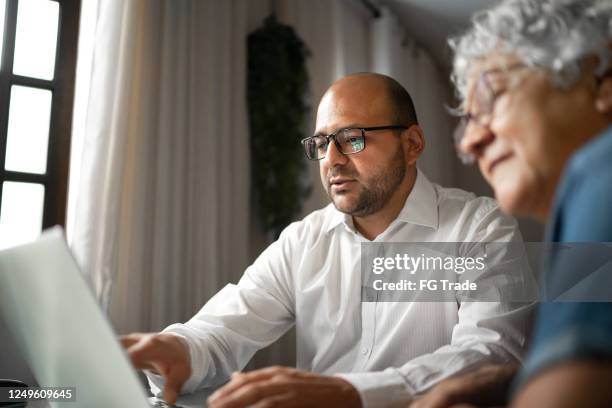 advisor helping a senior woman at home (or mother and son) - life insurance stock pictures, royalty-free photos & images