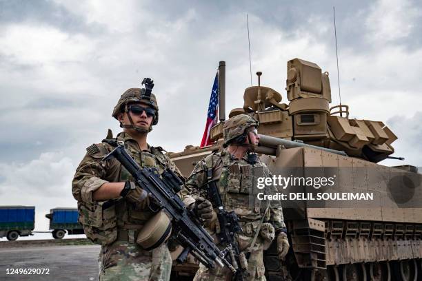 Army soldiers stand near an armoured military vehicle on the outskirts of Rumaylan in Syria's northeastern Hasakeh province, bordering Turkey, on...