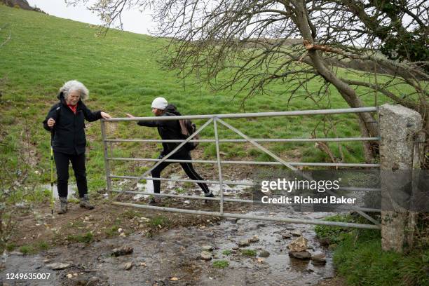 Two women walkers negotiate a wet section of the Southwest Coastal Path, on 23rd March 2023, in Mawnan, Cornwall, England.