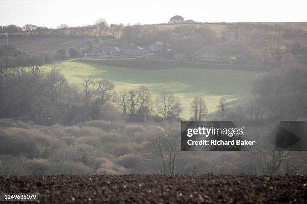 Farm land and a ploughed field in the foreground near the Cornish village of Mawnan Smith, on 19th March 2023, in Mawnan Smith, Cornwall, England.