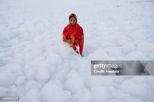 Hindu devotees perform rituals to the Sun god as they stand amid the polluted waters of the river Yamuna covered with a layer of toxic foam, on the...
