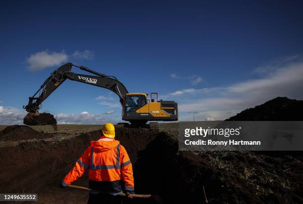 An archaeologist stands in front of an excavator digging on an archeological excavation on the site of a planned new Intel chip factory on March 27,...