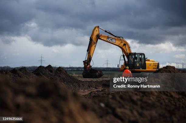 An archaeologist stands in front of an excavator digging on an archeological excavation on the site of a planned new Intel chip factory on March 27,...