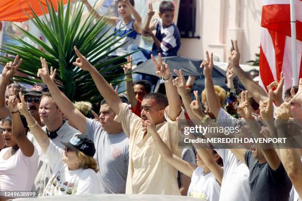 Protesters make the "V" sign while standing in front of the Miami home of Elian Gonzalez in Little Havana 04 April 2000 after they broke past...