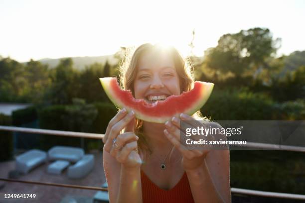 outdoor-porträt der lachenden jungen frau genießen wassermelone - balkon essen stock-fotos und bilder