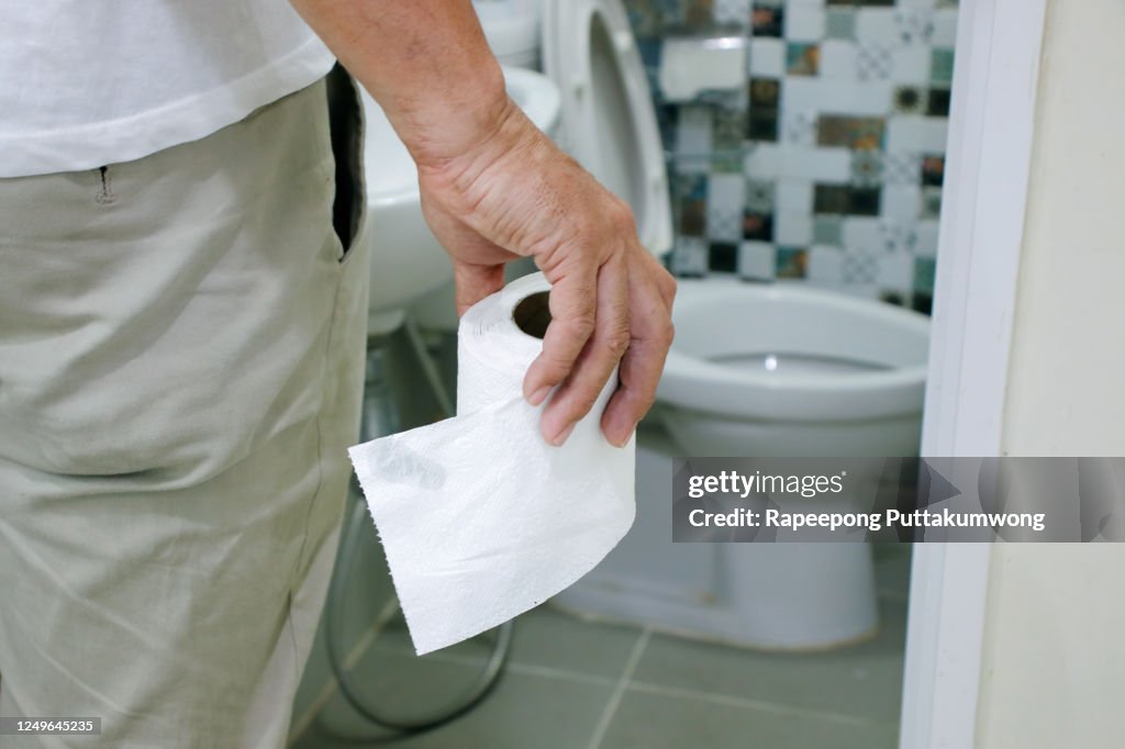 Man holding toilet tissue roll in bathroom