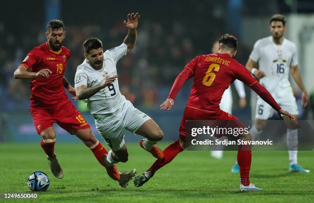 Aleksandar Mitrovic of Serbia in action against Aleksandar Scekic and Zarko Tomasevic of Montenegro during the UEFA EURO 2024 qualifying round group...