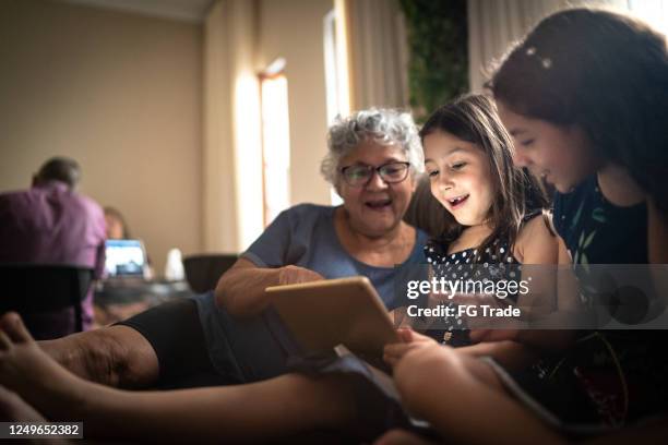 grootmoeder en kleindochter op een videogesprek met een digitale tablet thuis - it movie stockfoto's en -beelden