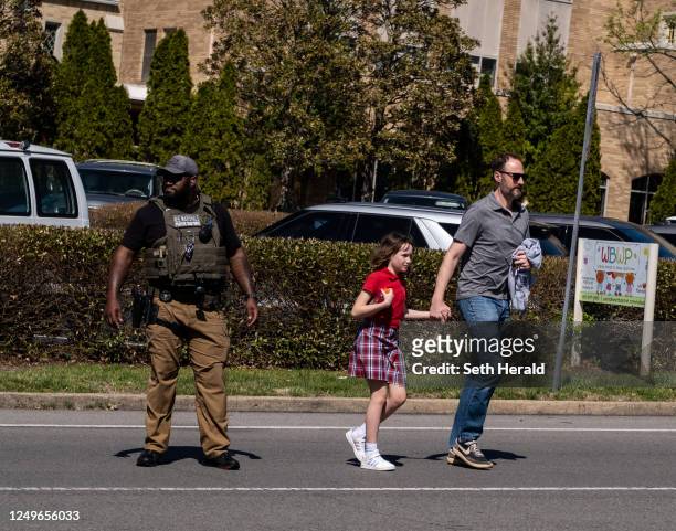 Parent walks with their child from Woodmont Baptist Church where children were reunited with their families after a mass shooting at The Covenant...