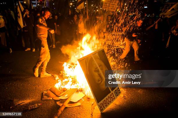 Israeli protester throws a placard showing Israeli Prime Minister Benjamin Netanyahu to a bonfire after clashes erupt during a demonstration against...