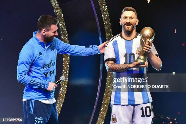 Argentina's forward Lionel Messi looks at a statue of himself during a tribute by Conmebol to the members of the Argentine national team for winning...