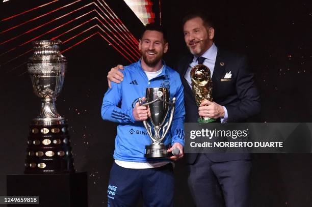 Argentina's forward Lionel Messi poses with the president of Conmebol, Paraguayan Alejandro Dominguez, next to the Copa America trophy while holding...