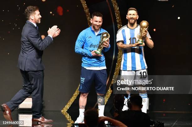 Argentina's forward Lionel Messi holds a replica of the World Cup trophy given to him by the president of Conmebol, Paraguayan Alejandro Dominguez ,...