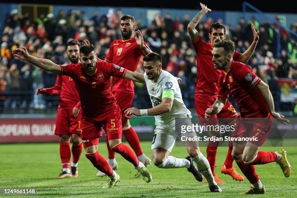 Dusan Tadic of Serbia in action against Igor Vujacic and Marko Vesovic of Montenegro during the UEFA EURO 2024 qualifying round group B match between...