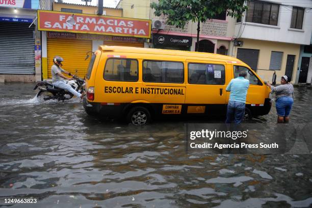 Driver of a school transport stands beside his vehicle after a heavy rain that flooded the area on March 27, 2023 in Guayaquil, Ecuador.