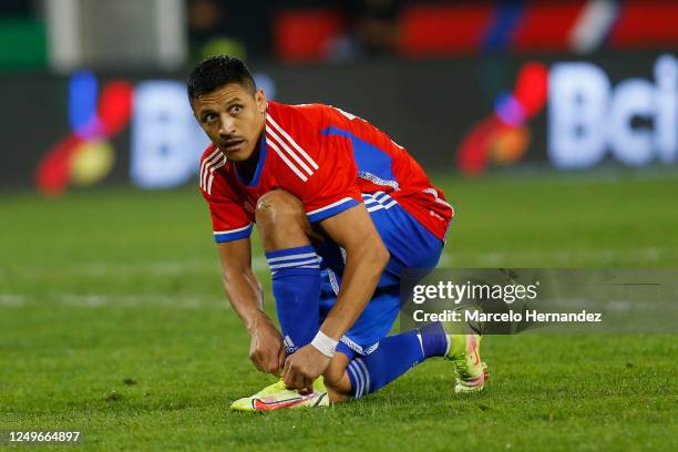 Alexis Sanchez of Chile ties his shoes during international friendly match against Paraguay at Estadio Monumental David Arellano on March 27, 2023 in...