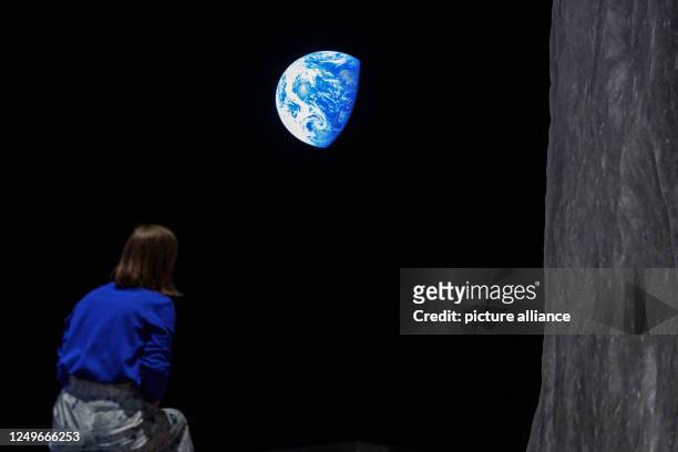 March 2023, Bavaria, Nuremberg: The photograph of the Earth "Earthrise", a NASA photo by William Anders showing the surface of the moon is projected...