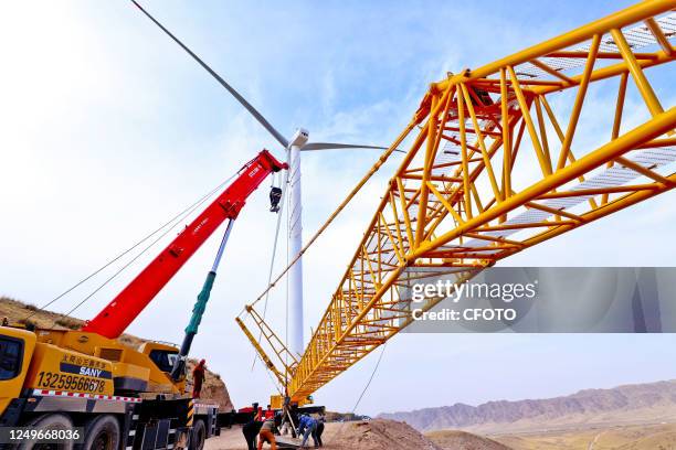 Builders disassemble large hangers at the construction site of a 49.5-megawatt wind farm project in Zhangye city, Gansu province, March 27, 2023.