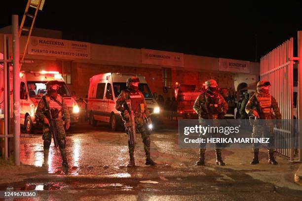 Firefighters and Mexican soldiers stand during a rescue for migrants from an immigration station in Ciudad Juarez, Chihuahua state on March 27 where...
