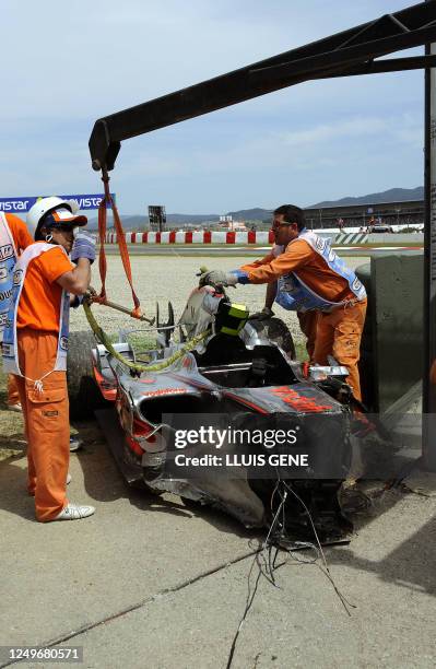 Crane lifts the car of McLaren Mercedes' Finnish driver Heikki Kovalainen fater he crashed during the Spanish Formula One Grand Prix, at the...