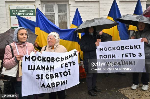 People hold placards reading "Moscow priests get away from Ukraine!" and "Moscow shaman get away from holy Lavra!" as they rally at the entrance to...