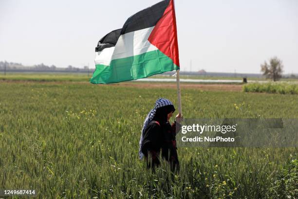 Palestinian woman holds a national flag during an event marking the 47th anniversary of Land Day, east of Gaza City by the border with Israel on...