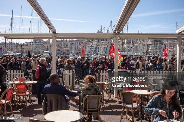 Customers in a cafe watch as protesters march past them during a demonstration against pension reform in Marseille, France, on Tuesday, March 28,...