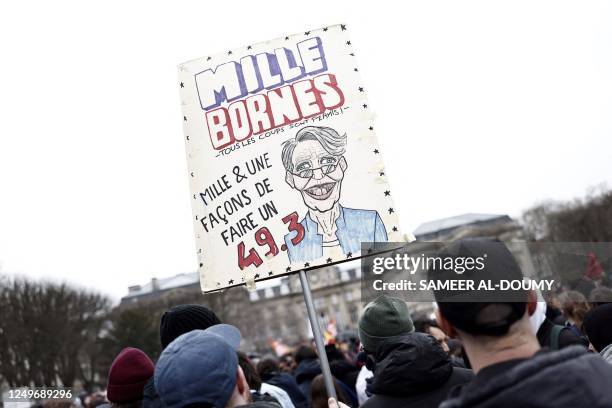 Protesters hold a placard with a drawing showing Prime Minister Elisabeth Borne during a demonstration after the government pushed a pensions reform...