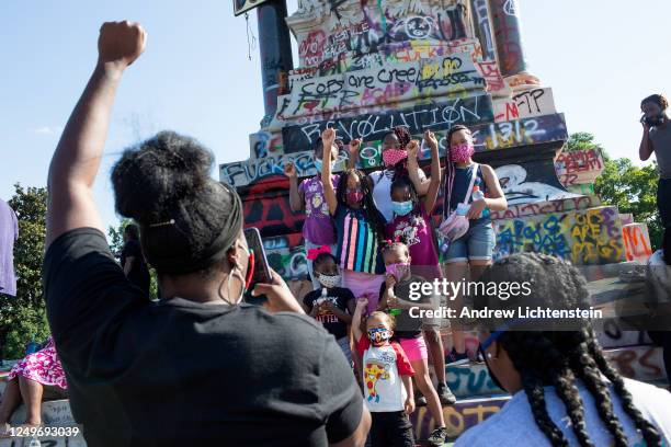 People visit the graffiti-covered statue of Confederate General Robert E. Lee on June 14, 2020 at Monument Avenue in Richmond, Virginia. The killing...