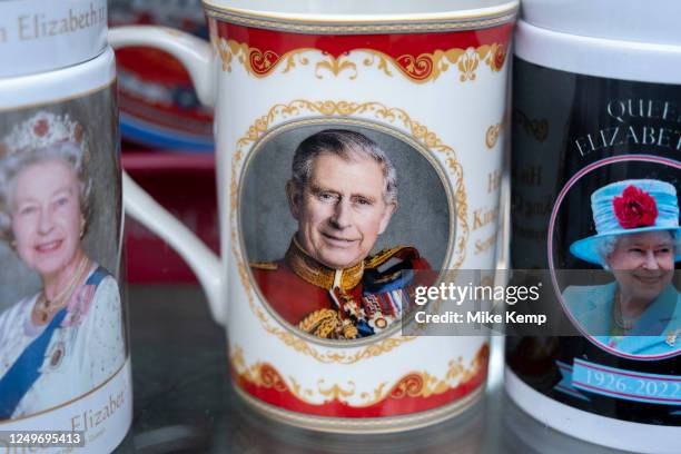 Mugs showing an image of a smiling King Charles III in ceremonial military uniform next to one of Queen Elizabeth II outside a souvenir shop on 27th...