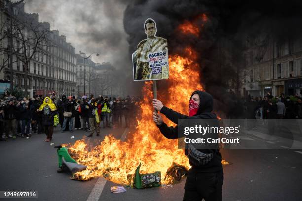 Protester holds a placard next to fire during a rally against pension reforms on March 28, 2023 in Paris, France. The country has experienced weeks...