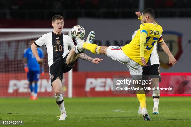 Angelo Stiller of Germany fights for the ball with Vladimir Screciu of Romania during the International Friendly match between U21 Romania and U21...