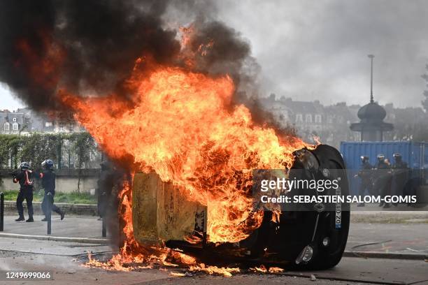 Car burns during clashes between demonstrators and riot-police on the sidelines of a demonstration after the government pushed a pensions reform...