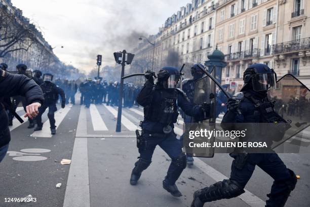 Riot police run with their batons during a demonstration after the government pushed a pensions reform through parliament without a vote, using the...