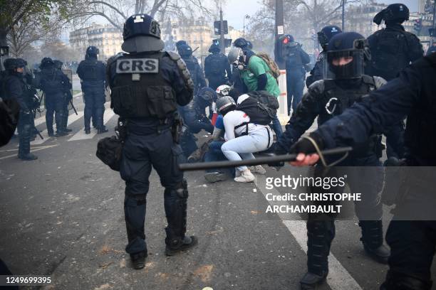 French anti-riot police forces and street medic help an injured man during a demonstration after the government pushed a pensions reform through...