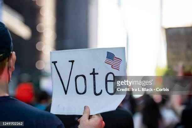 Protester holds a sign that reads, "Vote" with an American Flag as they march through the streets of New York City. This was part of the Warriors of...