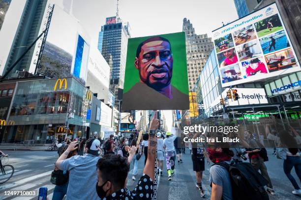Protesters wearing masks walk through the streets of Times Square holding up their hands and chanting, "Hands Up Don't Shoot" after police officers...