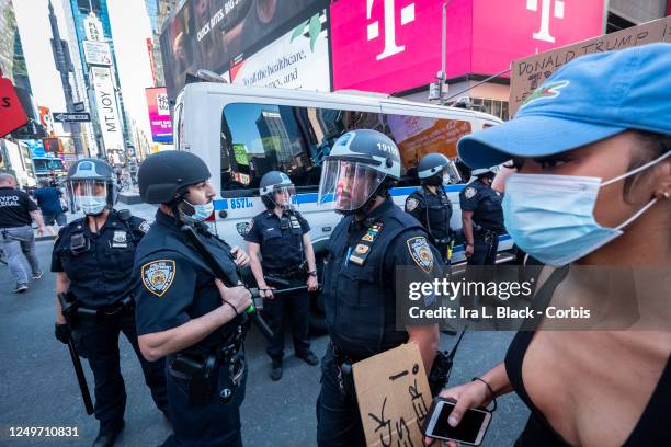 Protester wearing a mask walks past New York Police Department police officers conceded to let protesters that are trying to peacefully march through...