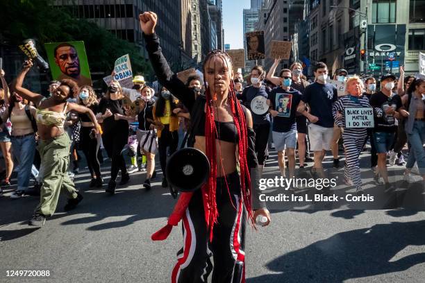 Livia Johnson, an organization leader for Warriors in the Garden holds a up her hand in a raised fist as she stands in front of hundreds of...