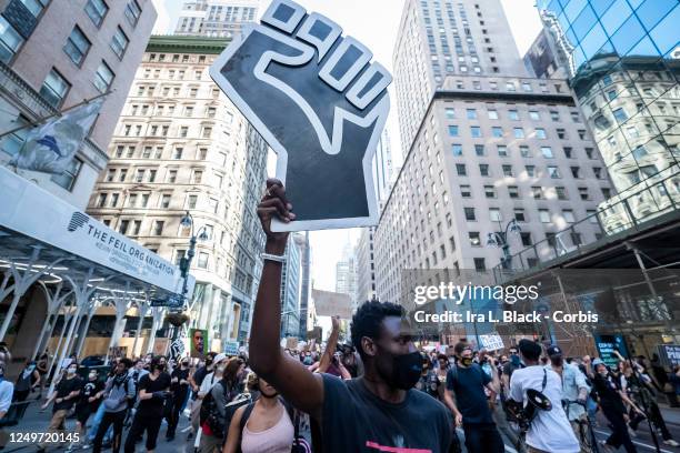 Protester holds a large black power raised fist through the streets of 5th Avenue in New York with hundreds of other protesters. This was part of the...