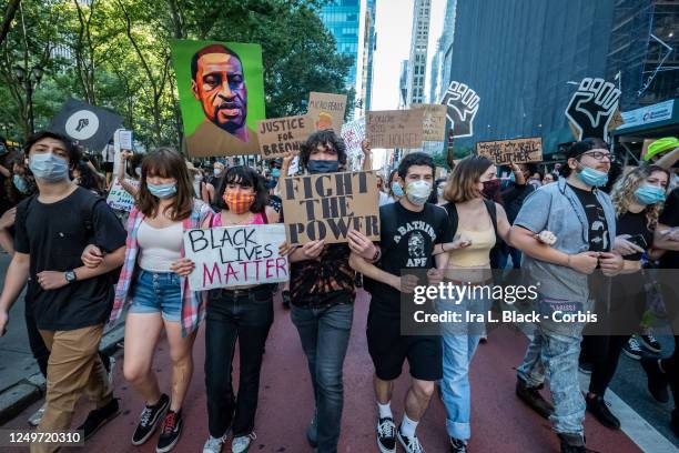 Protesters wearing masks and holding signs and pictures of George Floyd march arm in arm in a single line as they pass Bryant Park, This was part of...