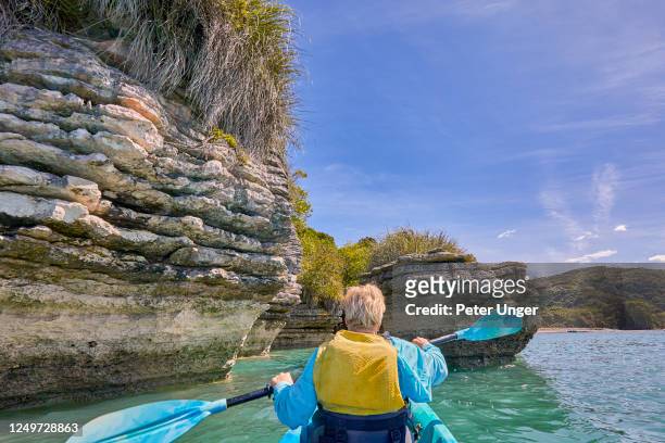 kayaking around the rock formations know as the pancake rocks at the town of raglan,waikato,north island,new zealand - summer new zealand stock-fotos und bilder
