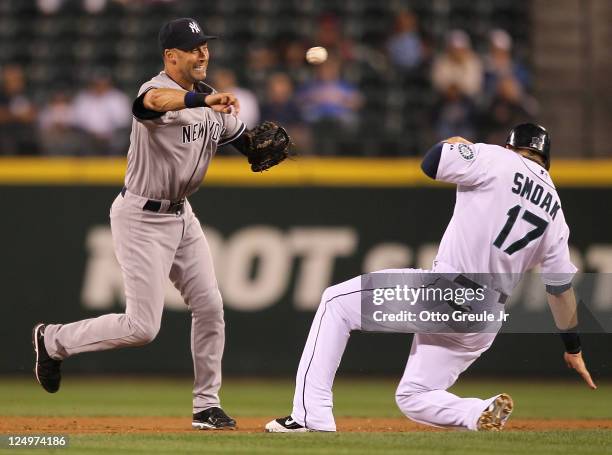 Shortstop Derek Jeter of the New York Yankees turns a double play over Justin Smoak of the Seattle Mariners at Safeco Field on September 14, 2011 in...