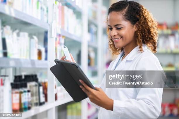 african american pharmacist checking products while working in pharmacy - black pharmacist stock pictures, royalty-free photos & images