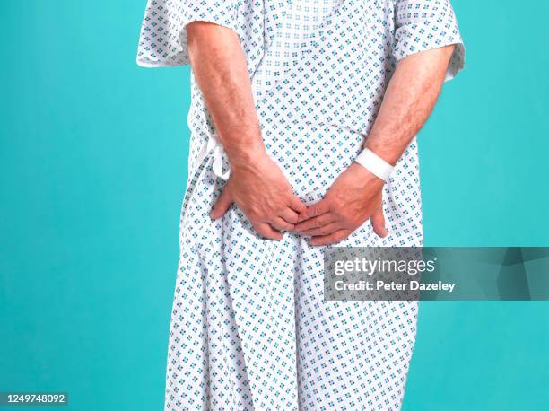 rear view of man in hospital gown, clutching buttocks - fart stock-fotos und bilder