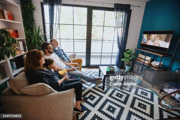 famille multi-génération regardant la tv et mangeant des pop-corn à la maison - grandmas living room photos et images de collection